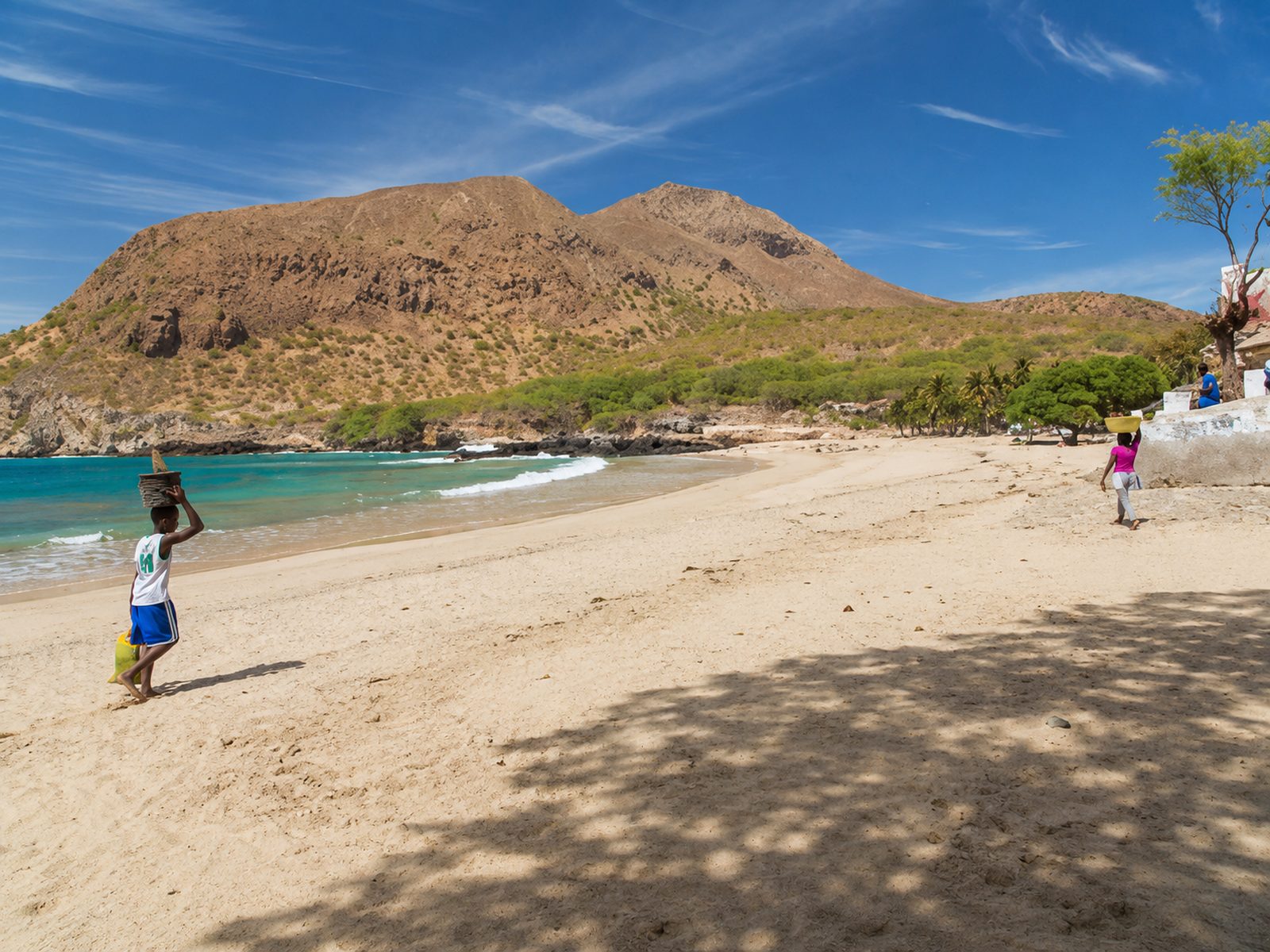 A wide empty golden-sand beach at sunset with gentle turquoise surf and dunes, Cape Verde
