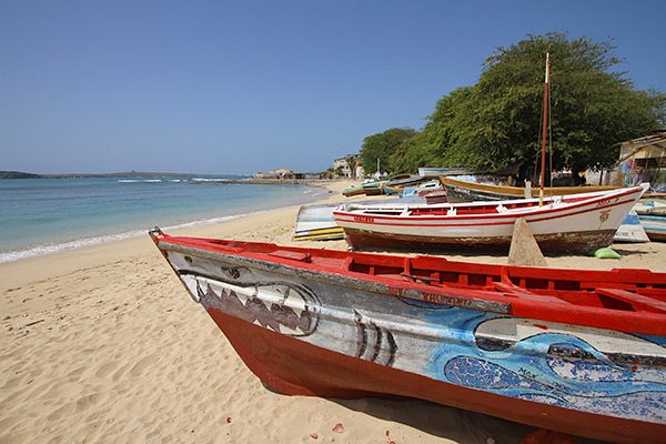 Brightly painted wooden fishing boats pulled up on the sand beside the calm bay at Sal Rei, Boa Vista