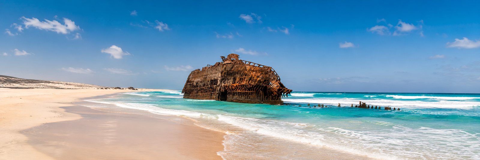 The rusting Cabo Santa Maria shipwreck on a white-sand beach with turquoise surf on Boa Vista, Cape Verde