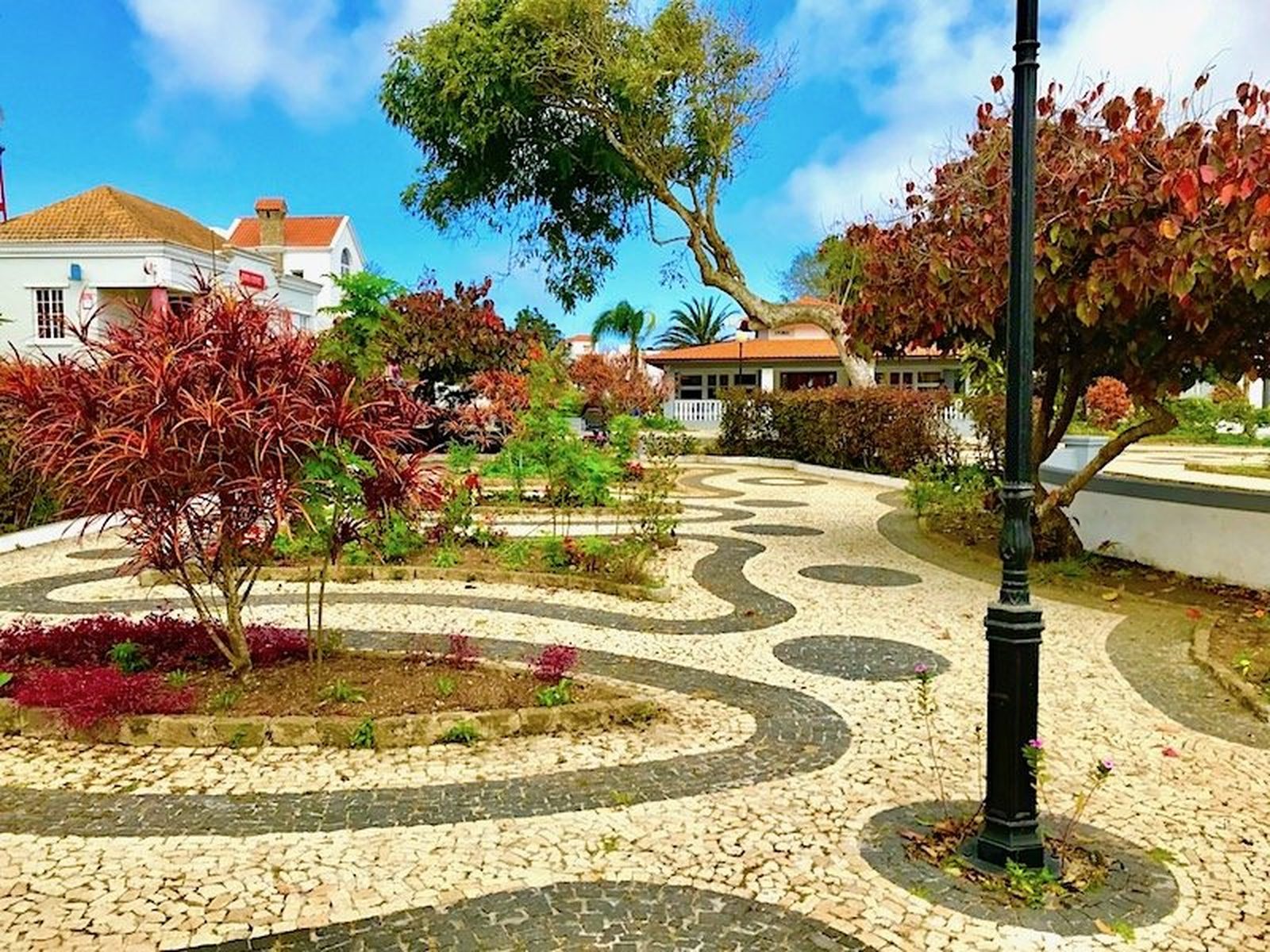 A tranquil town square with a traditional Portuguese cobbled pavement, garden beds and a lamp post, Cape Verde