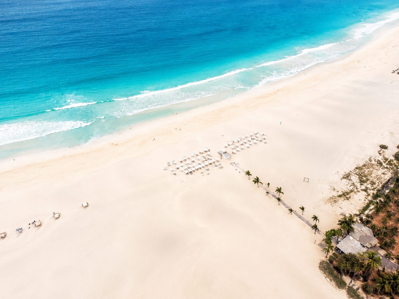 Aerial view of a beach resort with pools beside the dunes and long golden sand of Praia de Chaves, Boa Vista