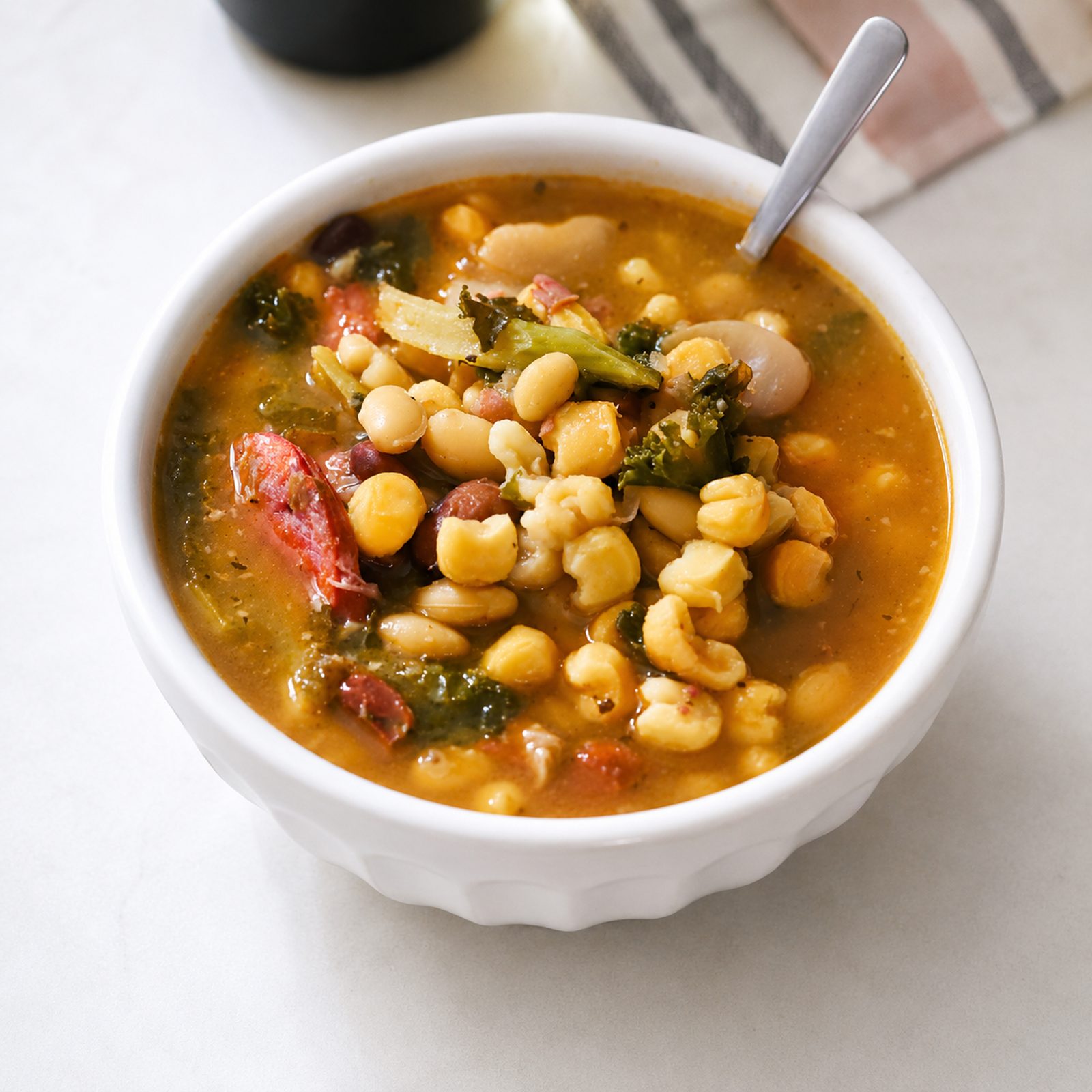 A bowl of cachupa, the Cape Verdean stew of corn, beans and vegetables with sausage, served with a spoon