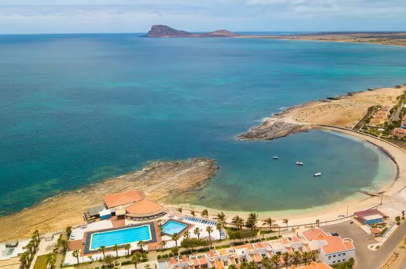 Aerial view of the sheltered, rock-edged bay at Murdeira on the west coast of Sal, Cape Verde, with a hotel pool in the foreground