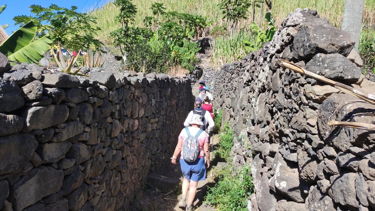 Hikers walking along a narrow path between high dry-stone walls on Santo Antão, Cape Verde