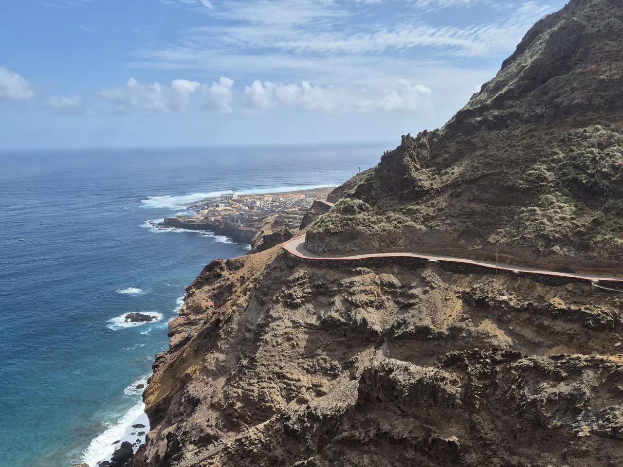 Narrow road climbing a cliff above the sea, with the town of Ponta do Sol on its headland in the distance, Santo Antão